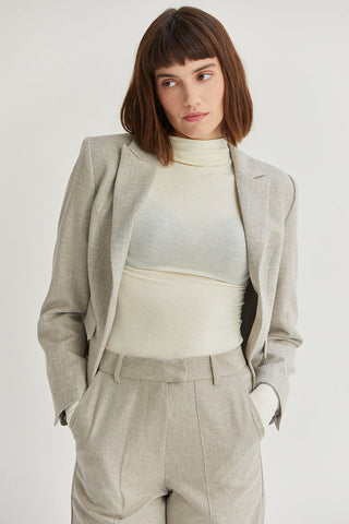 a model in a textured matching blazer and trousers over a cream turtleneck