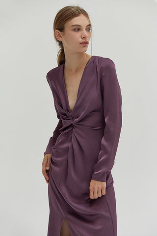 A woman wearing a textured satin dress with center front slit.