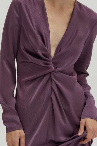 A woman wearing a textured satin dress with center front slit.