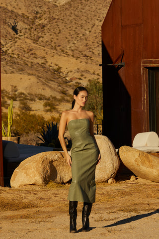 A woman wearing a green vegan leather midi tube dress.
