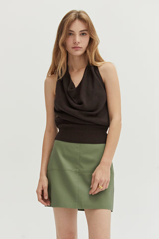 A woman wearing a green vegan leather mini skirt.
