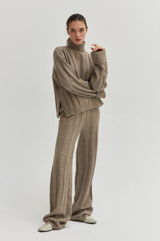 A woman wearing a ribbed sweater set with turtleneck top and pull on pants.