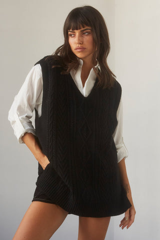 A woman wearing a black sweater vest over a white blouse