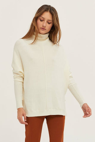 model wearing an ivory sweater with rust pants