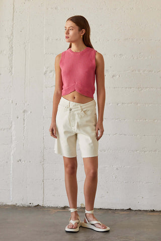 a model wearing white denim shorts and a pink cropped sweater top