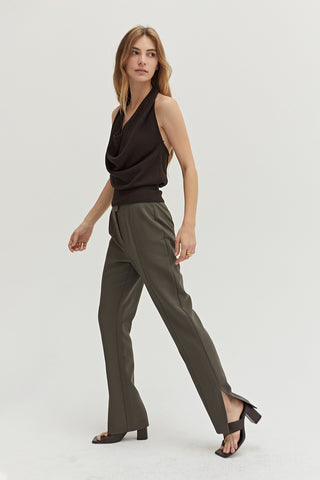 A woman wearing a dark olive straight leg trousers.