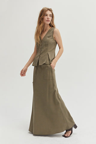A woman wearing a green maxi skirt with matching vest.