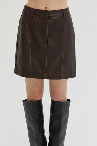A woman wearing a distressed vegan leather mini skit with pockets. 