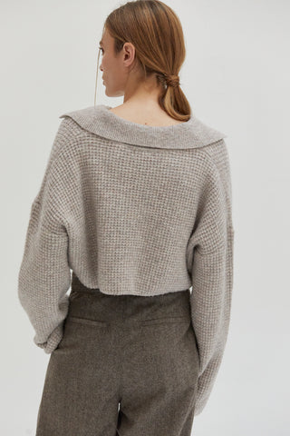 A woman wearing a waffle polo sweater. 