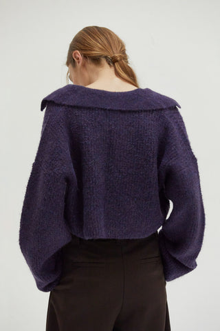 A woman wearing a waffle polo sweater. 