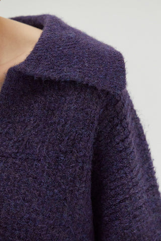 A woman wearing a waffle polo sweater. 