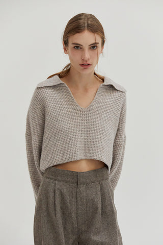 A woman wearing a waffle polo sweater. 