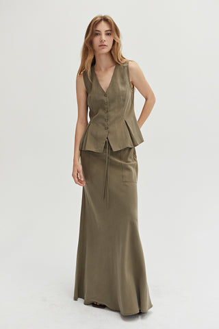 A woman wearing a green pleated vest features a V-neckline with matching skirt.