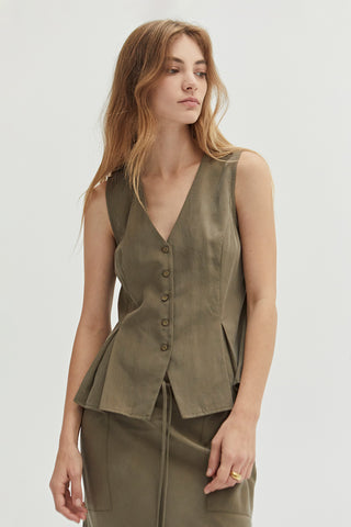 A woman wearing a green pleated vest features a V-neckline.
