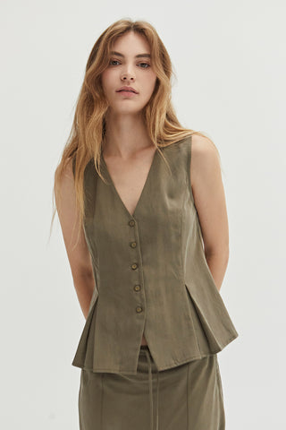 A woman wearing a green pleated vest features a V-neckline.