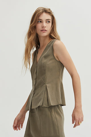 A woman wearing a green pleated vest features a V-neckline.