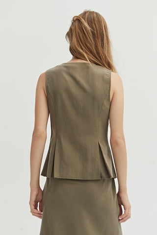 A woman wearing a green pleated vest features a V-neckline.