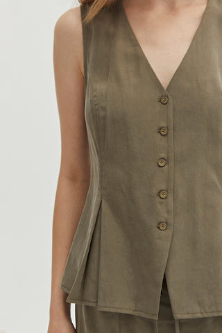 A woman wearing a green pleated vest features a V-neckline.