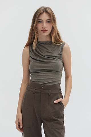 A woman wearing a high cowl neck sleeveless knit top.