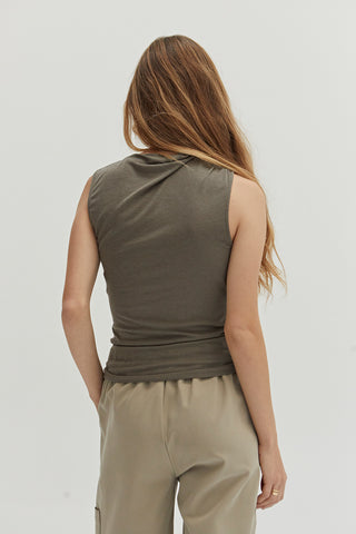 A woman wearing a high cowl neck sleeveless knit top.