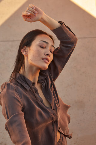 A woman wearing a cupro two piece bandeau & button up set.