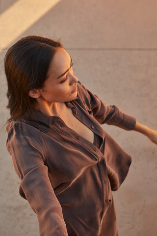 A woman wearing a cupro two piece bandeau & button up set.