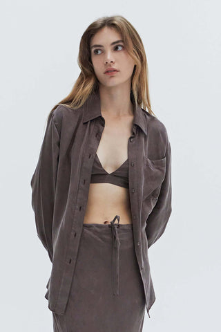 A woman wearing a cupro two piece bandeau & button up set.