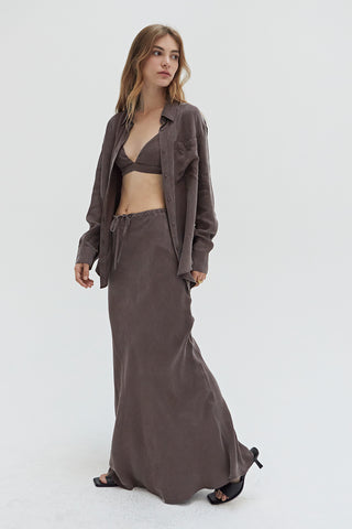 A woman wearing a cupro two piece bandeau & button up set with matching skirt.
