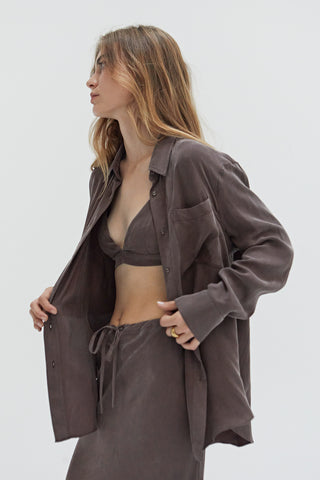 A woman wearing a cupro two piece bandeau & button up set.