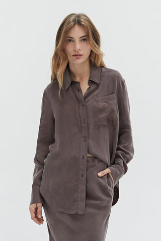 A woman wearing a cupro two piece bandeau & button up set.