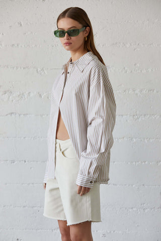 model wearing a beige pinstripe shirt with shorts