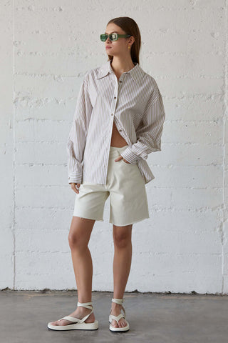 model wearing a beige and white button-up striped shirt