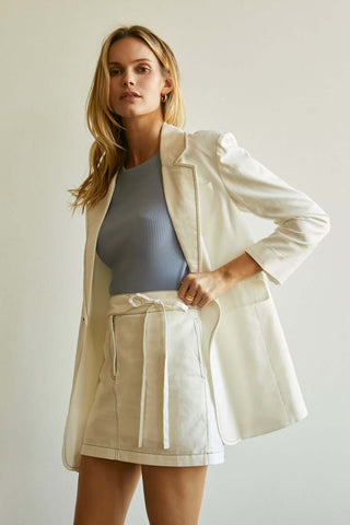model wearing a white denim blazer and skirt set