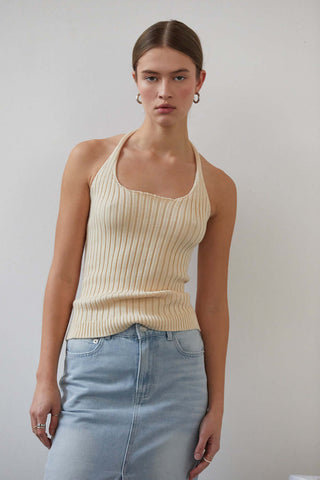 woman in cream top leaning to her left 