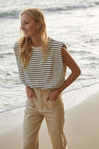 woman in striped top looking toward the right with pocketed hands