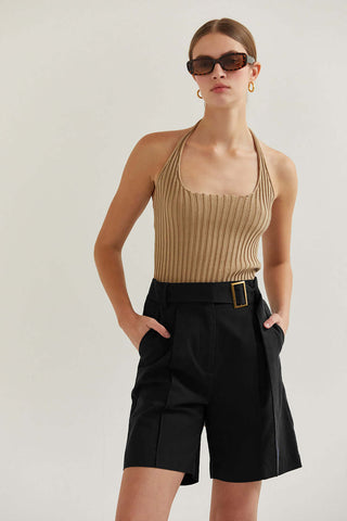 woman in taupe top with glasses leaning to her left