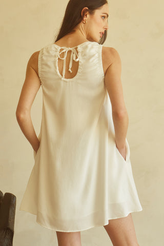 A woman wearing an ivory tencel mini dress.