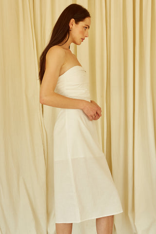 A woman wearing an ivory ruched bodice straight line midi dress.