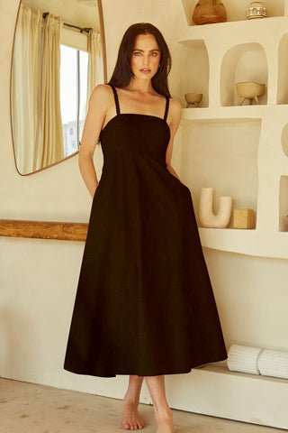 A woman wearing a black corset back midi linen dress.