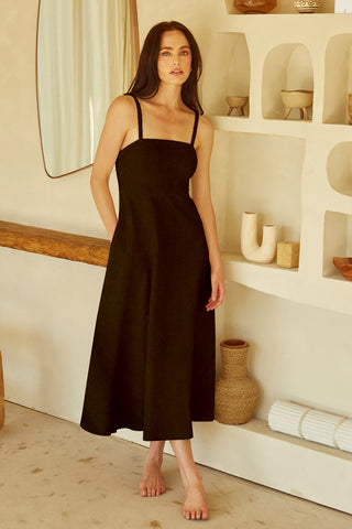 A woman wearing a black corset back midi linen dress.