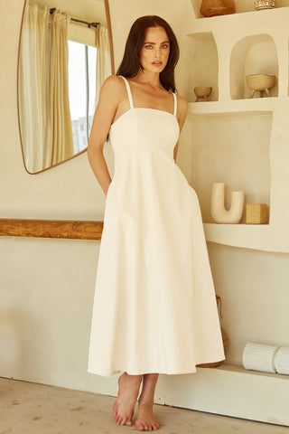 A woman wearing an ivory corset back midi linen dress.