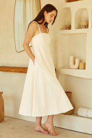 A woman wearing an ivory corset back midi linen dress.