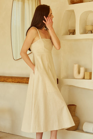 A woman wearing an oatmeal corset back midi linen dress.