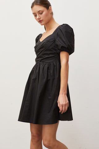 A woman wearing a black pleated front mini dress.