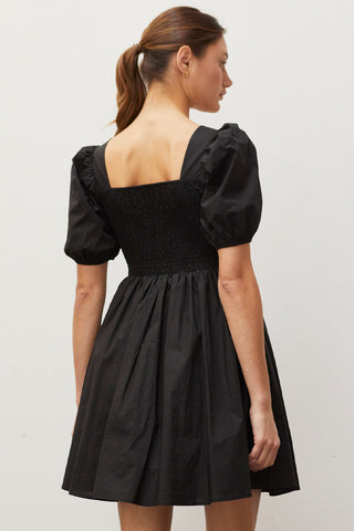 A woman wearing a black pleated front mini dress.