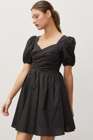 A woman wearing a black pleated front mini dress.