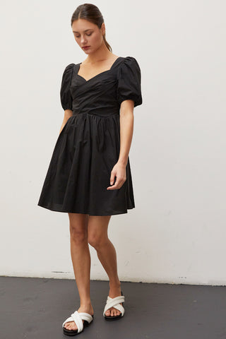 A woman wearing a black pleated front mini dress.