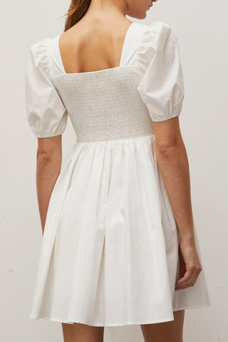 A woman wearing an ivory pleated front mini dress.