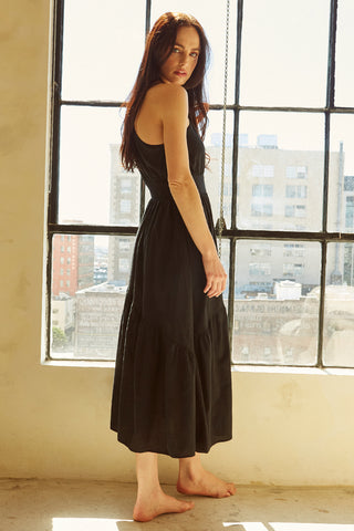 A woman wearing a black one-shoulder midi dress.