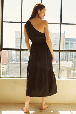 A woman wearing a black one-shoulder midi dress.